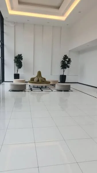 Room features: white painted walls, high ceiling with recessed lighting, large floor-to-ceiling windows, glossy white tile flooring, two potted plants, seating area with round ottomans, central coffee table with black frame; style: modern.
