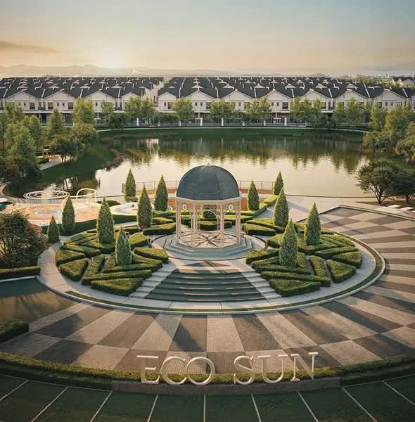 Exterior type: landscape garden; features: manicured lawn, mature trees, decorative gazebo, paved walkway, landscaped flower beds, view of the lake, surrounding residential buildings, outdoor seating area, children's playground, water feature, pathway with interlocking pavers; style: modern.