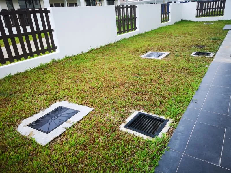 Exterior type: landscape garden; features: manicured lawn, drainage grates, fenced perimeter, paved walkway, green grass, concrete edging; style: modern.