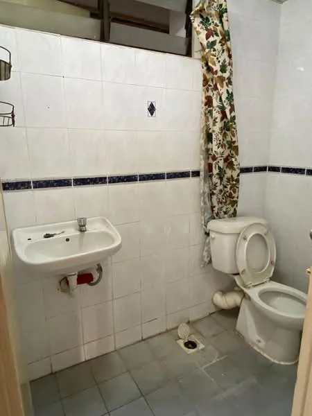 Bathroom features: white tiled walls, blue decorative border tiles, white ceramic sink, chrome faucet, toilet, shower area with drain, curtain for shower area, grey tiled flooring.