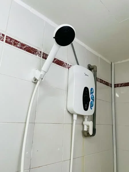 Bathroom features: white tiled walls, red decorative border tile, shower head with handheld attachment, electric water heater, chrome shower hose, wall-mounted shower holder.
