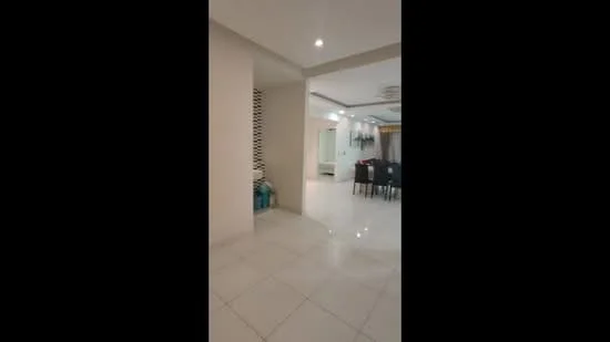 Room features: white painted walls, glossy tile flooring, recessed downlights, ceiling with crown moulding, open layout, dining area with black dining table and chairs, decorative wall feature, visible living area in background; style: modern.