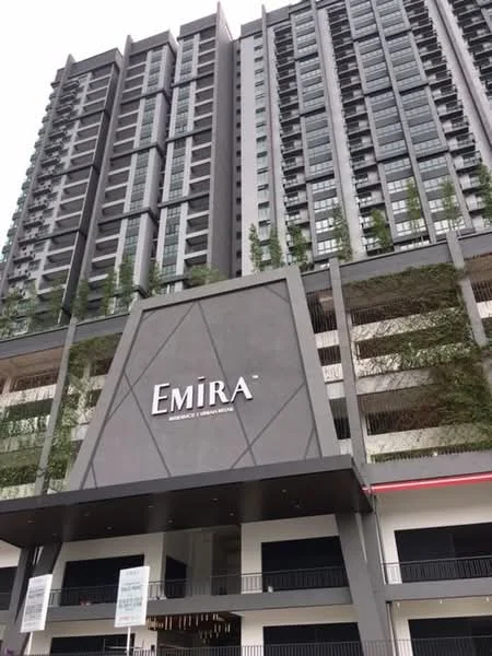 Exterior type: high-rise condominium; features: glass curtain wall, grey concrete facade, recessed balconies, vertical fins, feature lighting at night, manicured landscaping at base, signage with name 'EMIRA', multiple storeys, modern architectural design; style: modern.