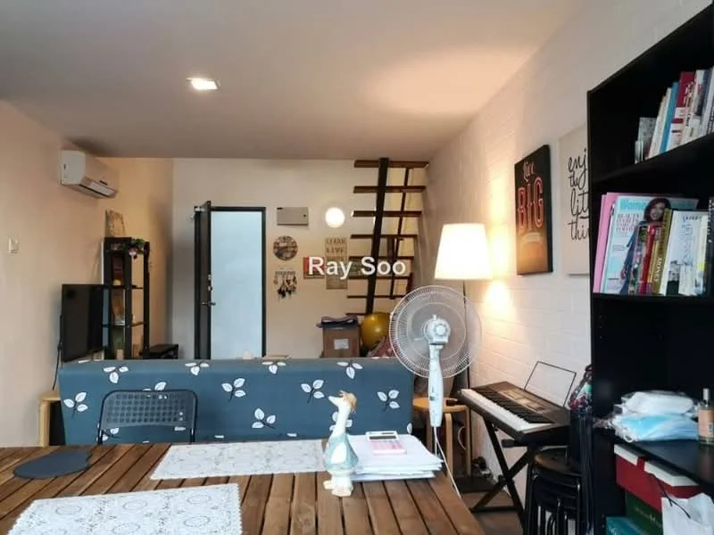 Living features: wooden flooring, white painted walls, exposed brick wall, 5-blade ceiling fan, wall-mounted air conditioning unit, sofa with floral pattern, coffee table, bookshelf with various books, floor lamp, piano, decorative items on the table, staircase leading to upper level; style: modern.