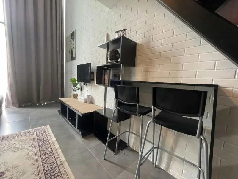 Living features: white painted walls, grey floor tiles, black shelving unit, flat-panel TV, bar counter with two black stools, decorative plant, area rug with intricate pattern, floor-to-ceiling windows with sheer curtains; style: modern.