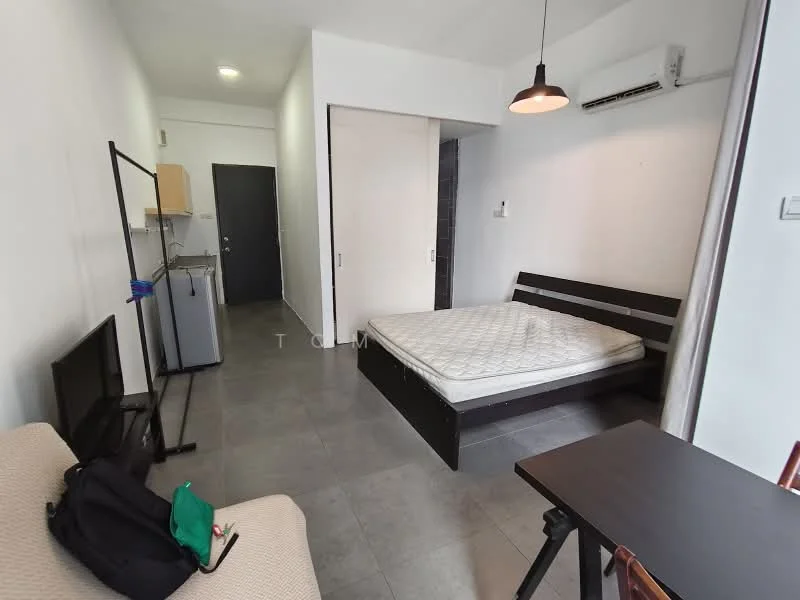 Room features: white painted walls, grey floor tiles, single bed frame without mattress, wall-mounted air conditioning unit, black bedside table, small dining table, sofa, TV on stand, kitchenette with wooden cabinetry, refrigerator, open shelving, light fixture, doorway leading to bathroom, sliding door closet; style: modern.