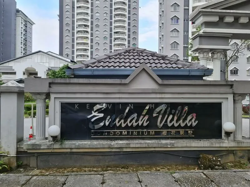 Exterior type: condominium; features: signage with name 'Endah Villa', decorative stone base, roof with tiles, surrounding greenery, paved walkway, multiple high-rise buildings in background; style: modern.