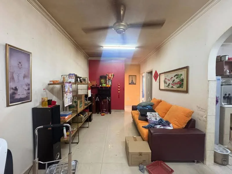 Living features: cream painted walls, white tiled flooring, 5-blade ceiling fan, orange fabric sofa, wooden shelving unit, decorative wall art, boxes on the floor, small table, doorway leading to another room.