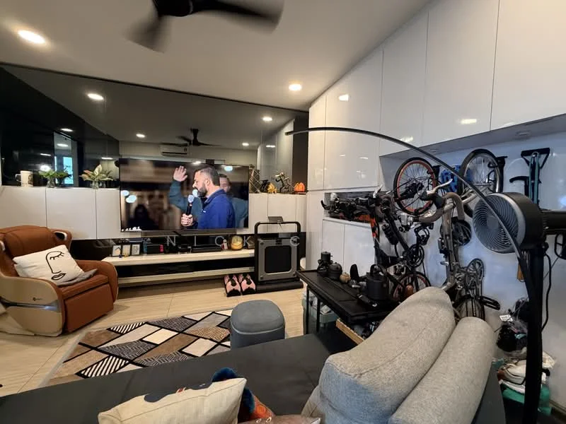 Living features: grey fabric sofa, 3-seater sofa, black coffee table, area rug with geometric pattern, wall-mounted TV, white cabinetry, light wood flooring, ceiling fan, decorative floor lamp, bicycle storage on wall, decorative items on shelves, black entertainment unit, pink slippers on floor; style: modern.