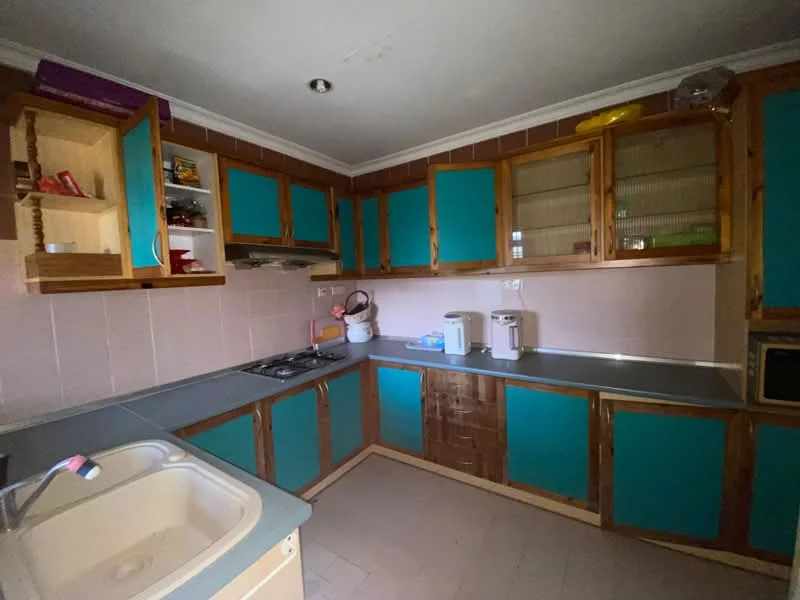 Kitchen features: blue cabinetry, wooden cabinetry, grey countertop, single-bowl sink, stainless-steel faucet, built-in gas hob, oven, tile backsplash, cream painted walls, laminate flooring, under-cabinet lighting; style: traditional.