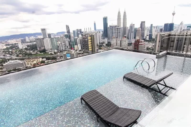 Exterior type: high-rise condominium; features: infinity pool, pool deck with loungers, city skyline view, glass railing, tiled pool surface, surrounding urban landscape, modern architecture; style: modern.