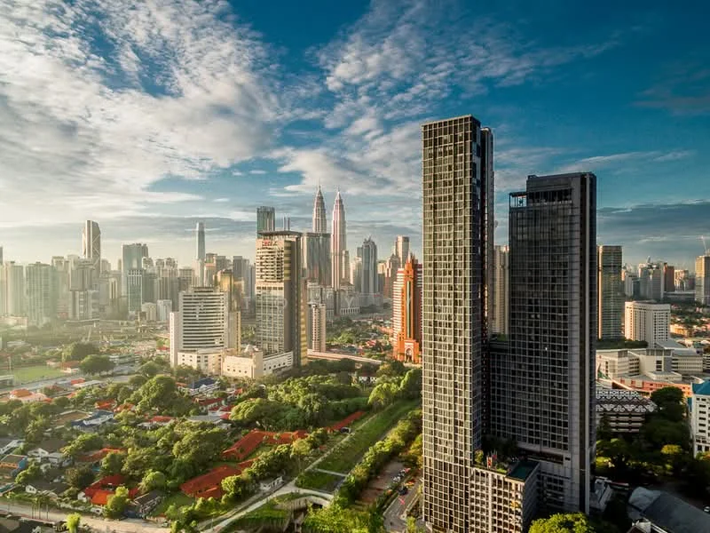 Exterior type: high-rise condominium; features: glass curtain wall, recessed balconies, surrounded by mature greenery, urban skyline view, approximately 20-storey high-rise, modern architectural design; style: modern.