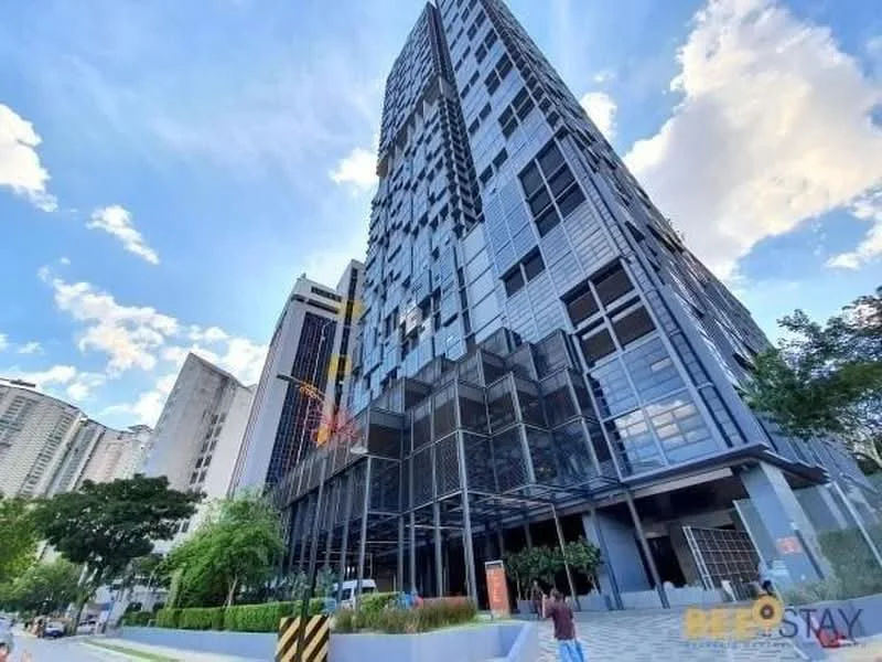 Exterior type: high-rise condominium; features: glass curtain wall, exposed concrete facade, recessed balconies, vertical fins, manicured landscaping, surrounded by mature greenery, driveway with interlocking pavers, double-volume main lobby, feature water wall; style: modern.