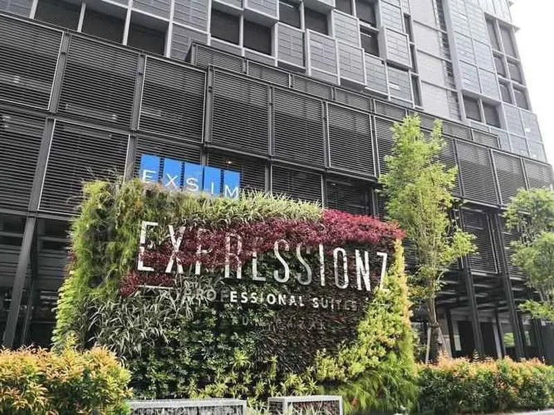 Exterior type: high-rise condominium; features: green wall with vertical garden, glass facade, metal louver screens, landscaped garden at base, signage with 'EXPRESSIONZ PROFESSIONAL SUITES', surrounding shrubs and plants, modern architectural design; style: contemporary.