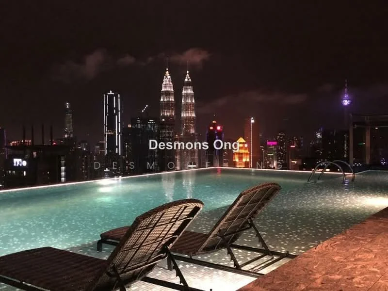 Exterior type: swimming pool deck; features: infinity pool with city skyline view, two lounge chairs, night lighting, surrounding cityscape, visible Petronas Twin Towers, visible KL Tower; style: modern.