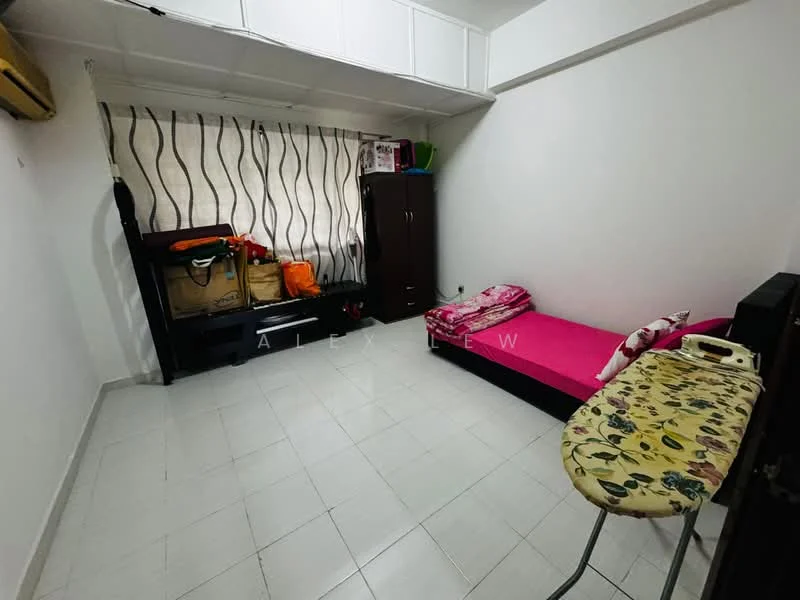 Bedroom features: single bed with pink bedding, white painted walls, white tiled flooring, floor-to-ceiling window with sheer curtains, built-in wardrobe, folding table with floral pattern, air conditioning unit, storage boxes, decorative pillows.