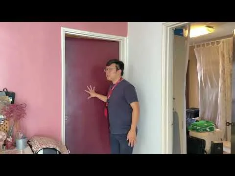 Room features: pink painted walls, white door, light-colored trim, visible door frame, carpeted flooring, decorative items on table, curtains in background, furniture partially visible.
