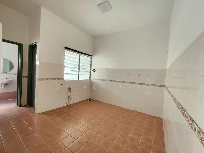 Room features: white painted walls, cream tiled wall cladding, brown tiled flooring, window with horizontal slats, light fixture on ceiling, plumbing visible on wall, decorative border tile, doorway leading to another room.