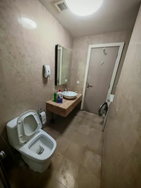Bathroom features: single-sink vanity with wood cabinet, chrome basin mixer faucet, framed mirror, one-piece toilet, tile cladding on walls, ceramic tile flooring, hand soap dispenser, toilet paper holder, washing machine, door with handle; style: modern.