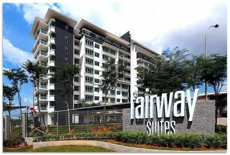 Exterior type: mid-rise condominium; features: modern facade with a mix of white and dark grey cladding, multiple balconies on upper floors, large windows, landscaped garden area in front, signage with the name 'fairway suites', surrounding trees, fenced perimeter, parking area visible; style: modern.