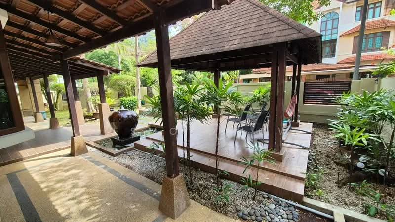 Exterior type: detached bungalow; features: wooden gazebo with thatched roof, decking area with outdoor chairs, landscaped garden with tropical plants, decorative water feature, stone pathway, exposed wooden beams, manicured lawn, surrounding greenery; style: tropical-modern.