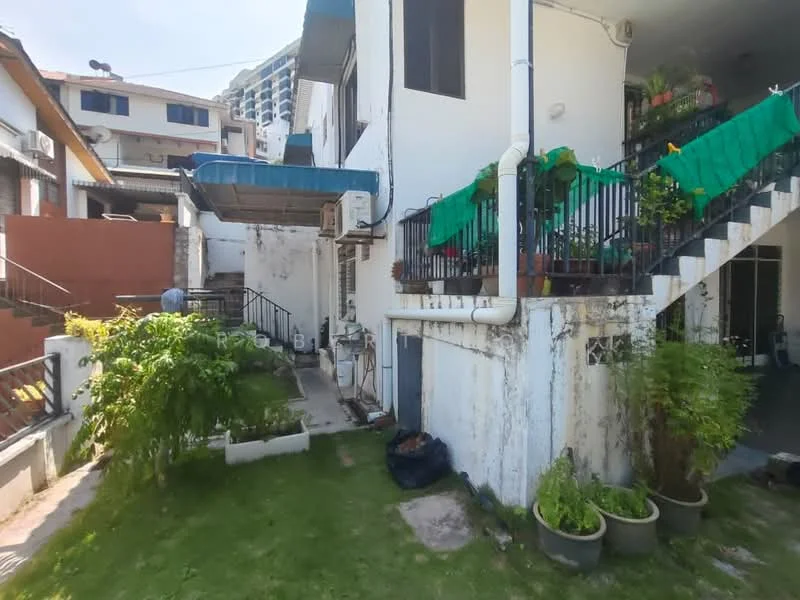 Exterior features: two-storey building, greenery in garden area, potted plants on ground, staircase leading to upper level, air conditioning unit visible, balcony with green tarpaulin cover, concrete pathway, fenced area, manicured lawn.