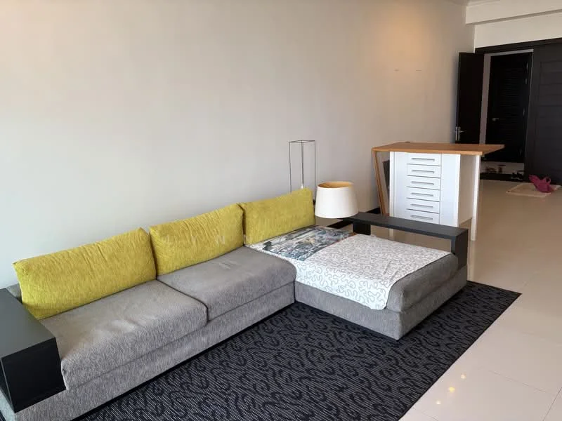 Living features: L-shape sectional sofa in grey, yellow accent cushions, black side table, area rug with geometric pattern, light fixture, open kitchen counter, cream painted walls, tile flooring; style: modern.