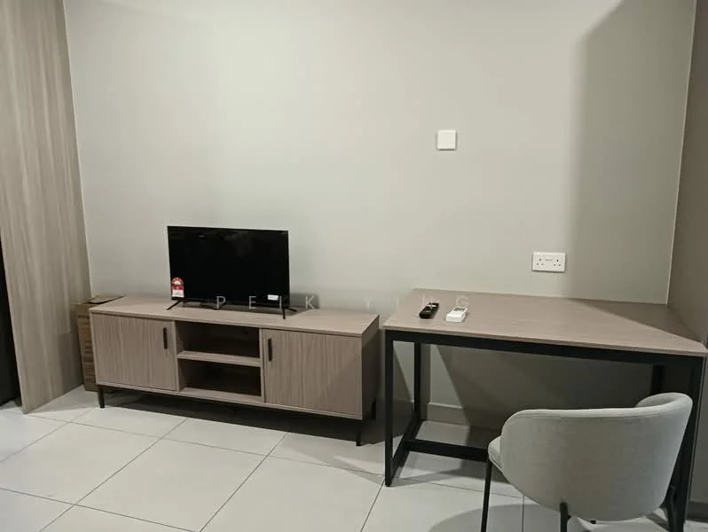 Room features: light grey painted walls, white tiled flooring, wooden TV console in light brown, black flat-screen TV, black remote control, white wall socket, light brown desk with black legs, grey upholstered chair; style: modern.