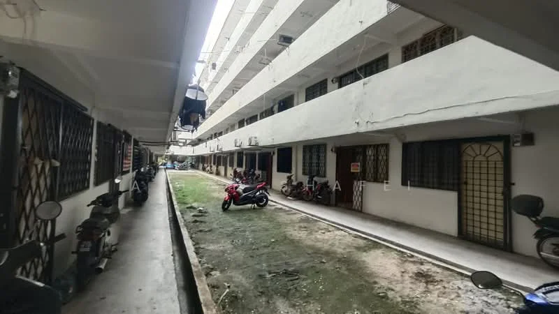 Exterior type: low-rise apartment block; features: two-storey building, concrete facade, balconies with metal railings, visible air conditioning units, motorcycle parking area, grass patch beside walkway, exposed utility lines, windows with security grilles; style: modern.