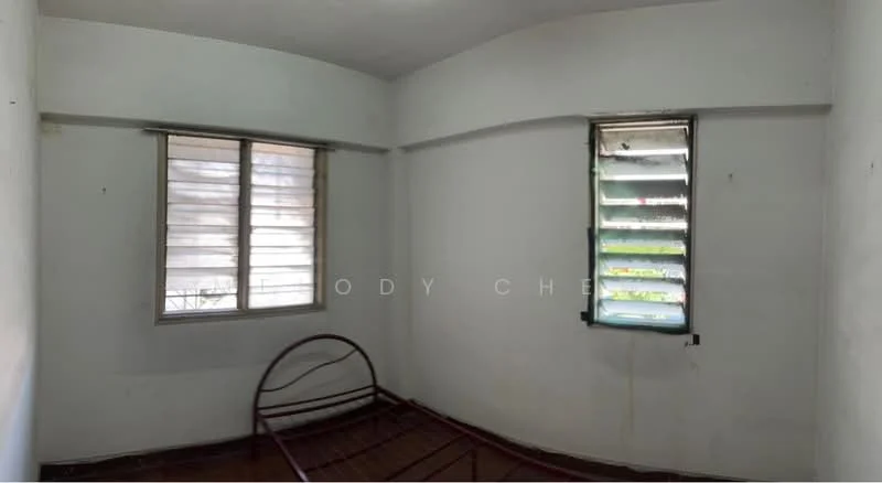 Room features: white painted walls, wooden flooring, two windows with green shutters, unframed bed frame, no visible decor, minimal natural light, corner room layout.