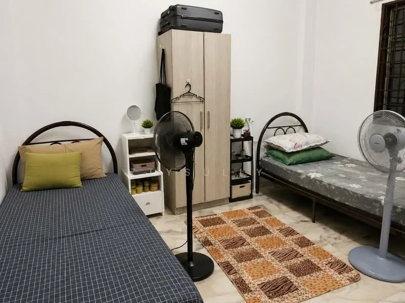 Bedroom features: two single beds, bedding with floral pattern, bedding with geometric pattern, wooden wardrobe, white painted walls, marble flooring, two standing fans, decorative area rug with animal print, small bedside table, greenery decor on shelves.