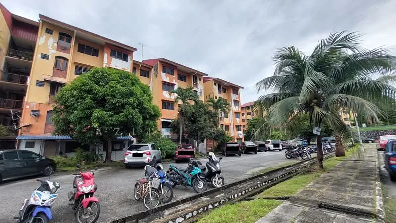 Exterior type: low-rise apartment block; features: yellow painted facade, green landscaping with palm trees, manicured lawn, parking lot with multiple vehicles, bicycle parking area, surrounding greenery, 2-storey building, balconies on upper floors; style: modern.