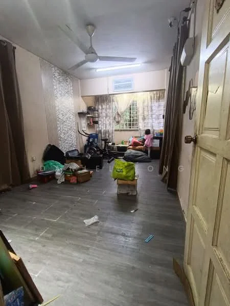 Room features: wooden flooring, white painted walls, ceiling fan, large window with sheer curtains, desk with chair, various boxes and items on the floor, decorative wall paneling, light-colored curtains, cluttered space.