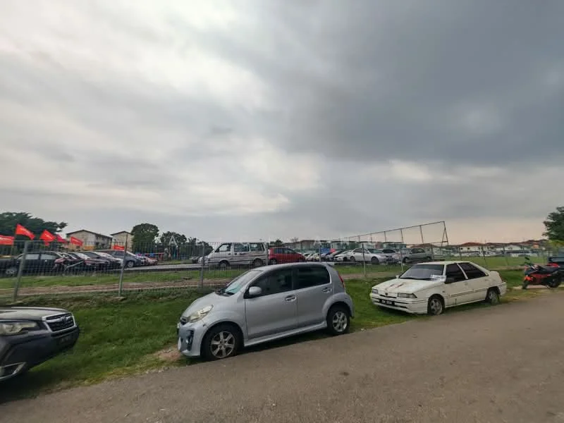 Exterior features: open-air parking lot, grassy area, fenced perimeter, multiple parked vehicles, cloudy sky.