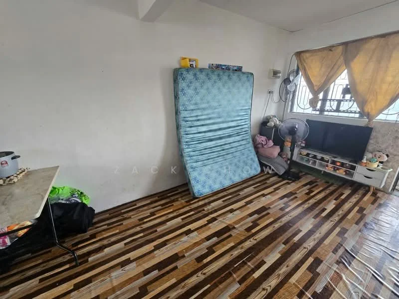 Room features: wooden flooring, white painted walls, large window with yellow curtains, wall-mounted fan, television on low cabinet, folding table, mattress on the floor, decorative items on cabinet.