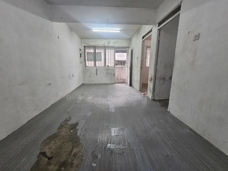 Room features: white painted walls, grey vinyl flooring, fluorescent ceiling lights, two doors leading to other rooms, window with metal grille, visible water stains on floor, bare walls with no decor, unfurnished space.