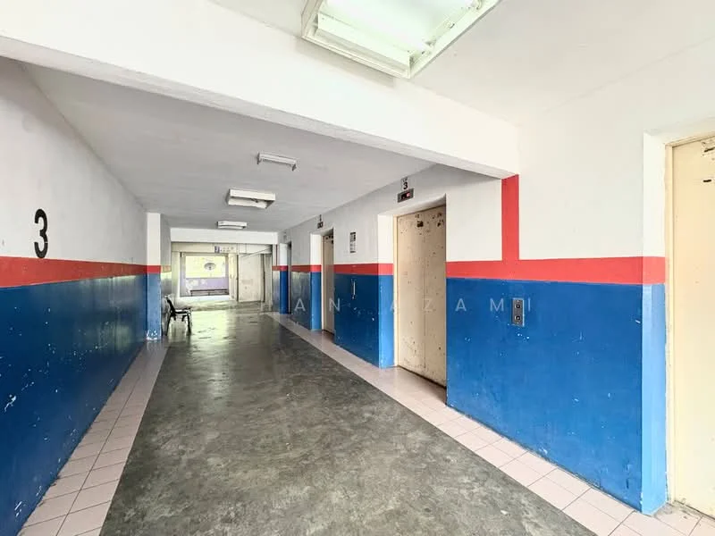 Room features: grey concrete flooring, white painted walls, blue and red accent walls, fluorescent ceiling lights, elevator doors, numbered doors, hallway, open space.