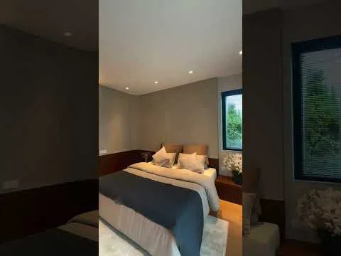Bedroom features: queen-size bed with grey bedding, upholstered headboard, two bedside lamps, wooden flooring, recessed downlights, large window with blinds, decorative plants in ceramic pots, neutral painted walls; style: modern; view: garden.