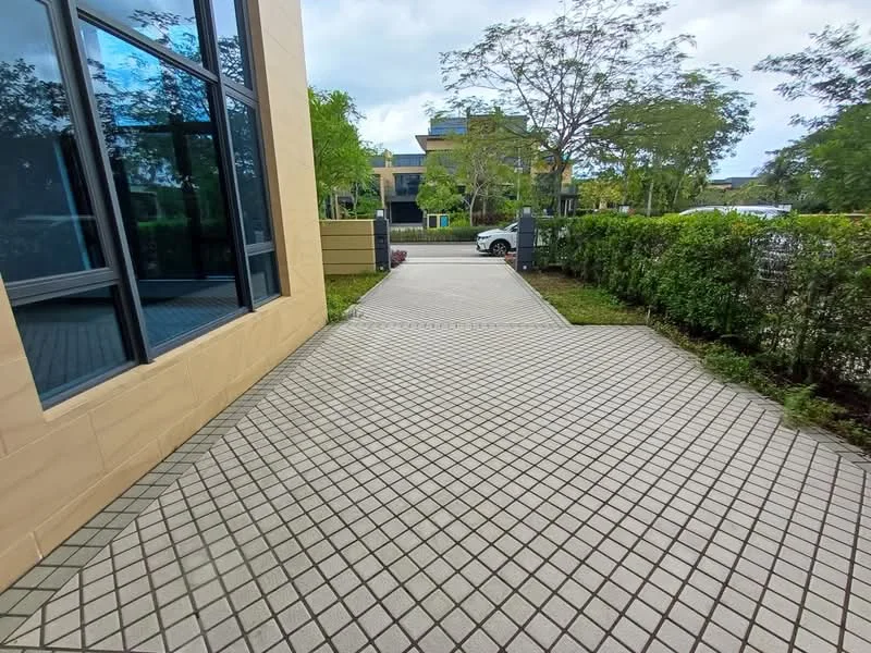 Exterior features: paved walkway, landscaped greenery, hedge border, large windows, modern facade, surrounding trees, parking visible in background; style: modern.
