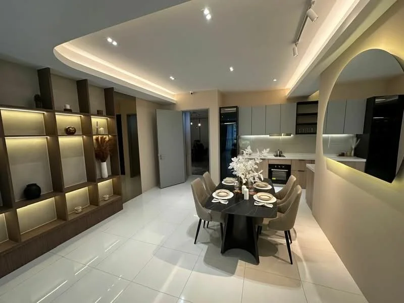 Dining features: round dining table, upholstered dining chairs, decorative centerpiece with flowers, wall-mounted shelves with decorative items, recessed LED downlights, cream painted walls, glossy white tile flooring, built-in cabinetry, kitchen area in background with modern cabinetry, open-plan layout; style: modern.
