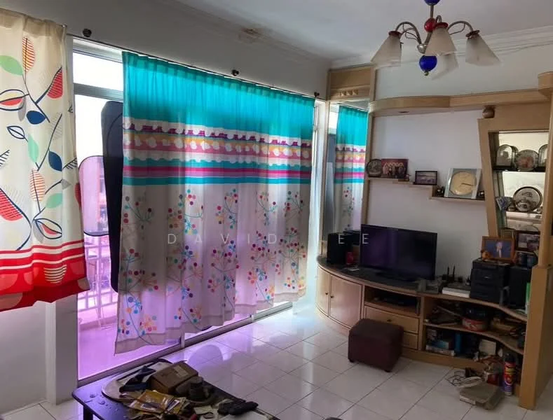 Living features: white painted walls, glossy tile flooring, ceiling light fixture with multiple bulbs, curtains with colorful patterns, TV console, wall-mounted TV, decorative shelves, various decorative items on shelves, coffee table, cluttered floor space.