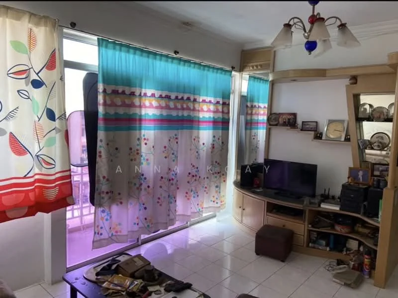 Living features: white tiled flooring, curtains with colorful floral patterns, built-in wooden TV console, wall-mounted TV, decorative shelves, ceiling light fixture with multiple bulbs, coffee table, various decorative items on shelves, small ottoman, open window with balcony access.