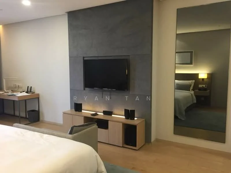 Room features: light wood flooring, grey accent wall, wall-mounted TV, wooden TV console, black speakers, desk with chair, table lamp, large mirror, bed with white bedding, decorative wall art; style: modern.