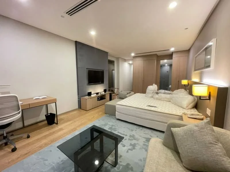 Room features: queen-size bed, upholstered headboard, light grey sofa, glass coffee table, wooden flooring, white painted walls, recessed downlights, wall-mounted TV, built-in wardrobe, study desk with chair, desk lamp, bedside lamps; style: modern.