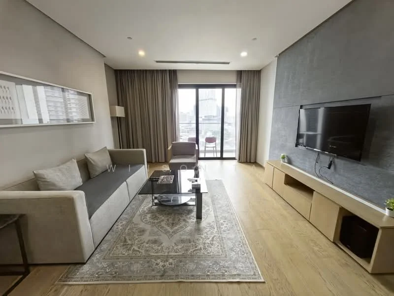 Living features: grey fabric sofa, glass coffee table, TV console with storage, wall-mounted TV, area rug with intricate pattern, floor-to-ceiling windows, curtains, wooden flooring, decorative plant, accent chair in purple; style: modern; view: city.