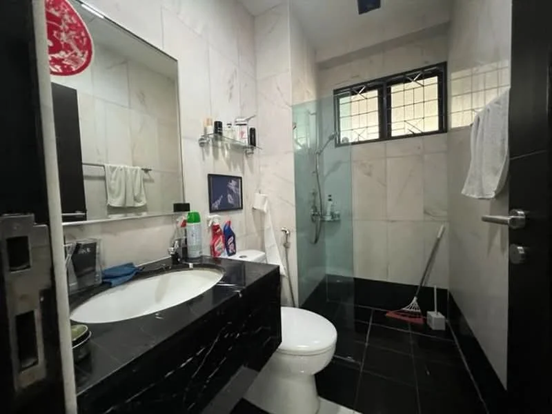 Bathroom features: single-sink vanity with black cabinet, mirror above sink, white toilet, walk-in shower with glass enclosure, chrome shower head, black tile flooring, white marble wall tiles, towel rack, window for natural light, cleaning supplies visible; style: modern.