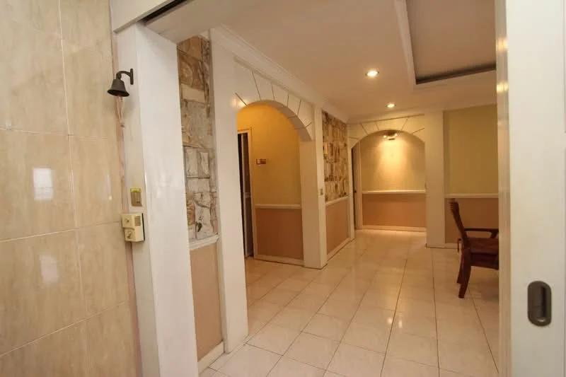 Room features: cream tiled flooring, white painted walls, exposed stone accent wall, arched doorways, recessed lighting, wall-mounted light fixture, crown moulding, decorative wall paneling; style: modern.