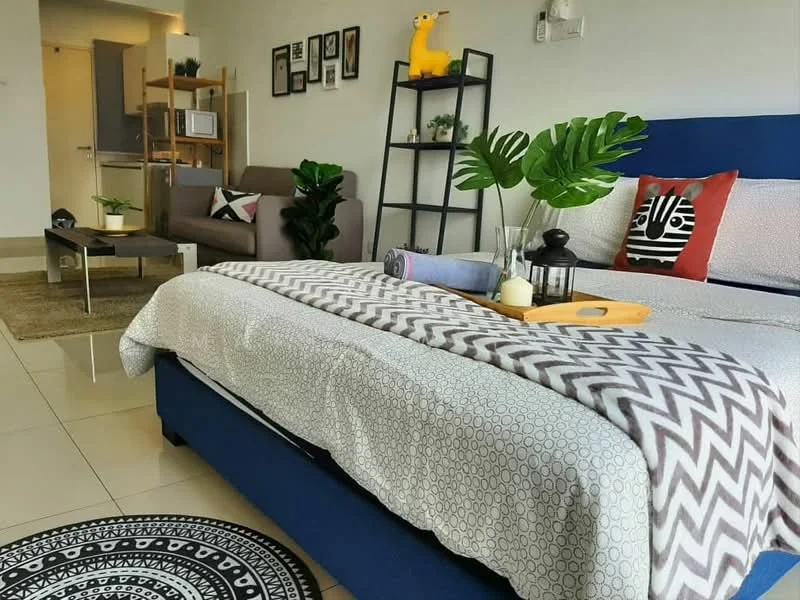 Living features: queen-size bed with patterned bedding, upholstered headboard, 2-seater fabric sofa in grey, coffee table, area rug with geometric pattern, decorative pillows, wall-mounted shelves, houseplants in ceramic pots, framed artwork on walls, floor-to-ceiling windows, light-colored tiled flooring, table lamp, throw blanket; style: modern.