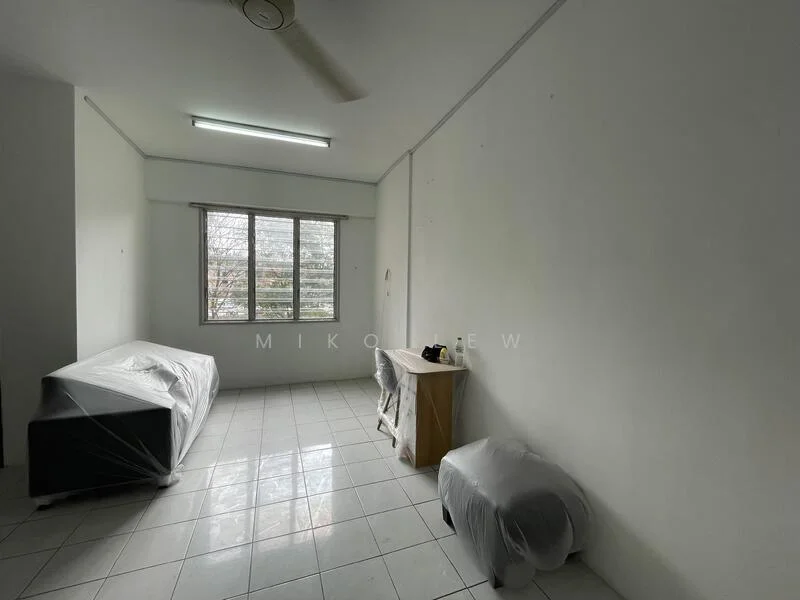 Room features: white painted walls, white tiled flooring, ceiling fan, large window with blinds, single bed with protective covering, wooden side table, plastic covering on furniture.
