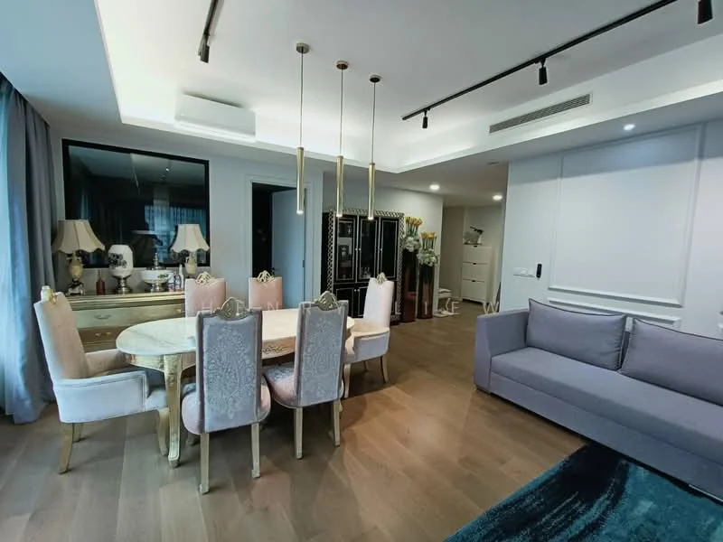 Dining features: round dining table, upholstered dining chairs in pink, chandelier with multiple pendants, wooden flooring, wall-mounted mirror, decorative wall paneling, floor-to-ceiling windows with sheer curtains, sofa in grey fabric, decorative plants, recessed ceiling lights; style: modern.